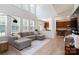 Spacious living room with soaring ceilings, large windows, and a comfortable gray sectional sofa adjacent to the kitchen at 12341 Mcallister Park Dr, Charlotte, NC 28277