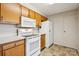 A kitchen featuring wooden cabinets, white appliances, and tiled floors at 1300 Reece Rd # 305, Charlotte, NC 28209