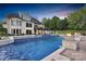 Beautiful backyard with a luxurious pool, a spa, and fire bowls for elegant outdoor living at dusk at 1430 Rosehill Dr, Waxhaw, NC 28173