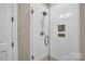 Modern shower featuring textured white tiles, a glass door, built-in shower caddy, and pebble tile flooring at 1430 Rosehill Dr, Waxhaw, NC 28173