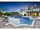 Gorgeous pool and outdoor living space featuring fire bowls, a spa, and views of the home at dusk at 1430 Rosehill Dr, Waxhaw, NC 28173