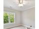 Bright bedroom featuring neutral walls, plush carpeting, ceiling fan, and double window with lush greenery view at 18618 Rollingdale Ln, Davidson, NC 28036