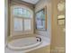 Relaxing bathroom featuring a jetted tub with tile surround and plantation shutters at 213 Cowboys Cir, Rock Hill, SC 29732