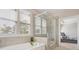 Bright bathroom features tile, separate tub, frameless glass shower, and view into bedroom at 500 Landau Rd, Waxhaw, NC 28173
