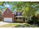 Charming two-story brick home with a covered porch and attached two-car garage, showcasing curb appeal at 6800 Augustine Way, Charlotte, NC 28270