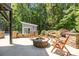 Inviting stone patio featuring a fire pit, seating, and a backdrop of lush trees and foliage at 6800 Augustine Way, Charlotte, NC 28270