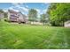 Manicured backyard with lush lawn, mature trees, and a home with a wooden deck at 7731 Sedgebrook E Dr, Stanley, NC 28164