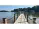 Long wooden dock with black rope railings extending out onto a peaceful lake, with calm waters and wooded shores in the background at 126 Aqua Dr, Mooresville, NC 28117