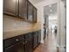 Hallway view of the kitchen featuring dark cabinets, granite countertops, stainless steel appliances, and hardwood floors at 12704 Franklin Square Rd, Charlotte, NC 28213