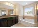 Bright main bathroom with a soaking tub, double vanity, and granite countertops at 12704 Franklin Square Rd, Charlotte, NC 28213