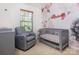 Charming Bedroom with floral accent wall, crib, and cozy grey chair near a window at 2273 Aston Mill Pl, Charlotte, NC 28273