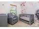 Comfortable Bedroom with grey rocking chair, crib, and lovely floral wallpaper feature wall and a window at 2273 Aston Mill Pl, Charlotte, NC 28273