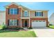 Charming two-story home featuring a brick facade, attached garage, and well-maintained front lawn at 2357 Riding Trail Rd, Gastonia, NC 28054