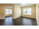Open-concept living room with wood laminate flooring and abundant natural light from multiple windows at 2357 Riding Trail Rd, Gastonia, NC 28054
