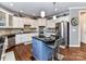 Bright eat-in kitchen with white cabinets, stainless steel appliances, hardwood flooring, and a blue island at 27246 Preston Pl, Fort Mill, SC 29707
