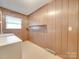 Functional laundry room featuring wood-paneled walls, open shelving, and ample space at 3113 Old Pageland Marshville Rd, Wingate, NC 28174