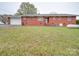 Rear exterior showcasing the brick home with an attached garage, lawn, and storage tank at 3113 Old Pageland Marshville Rd, Wingate, NC 28174