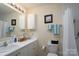Bright bathroom featuring a white vanity and toilet, framed mirror and shower with curtain at 407 Hertling Nw Dr, Concord, NC 28027