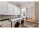 Bright laundry room with white cabinets, modern appliances, and convenient storage shelf at 600 Beauhaven Ln, Waxhaw, NC 28173