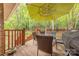 Enjoy outdoor dining on the wooden deck with a green umbrella, table and grill overlooking wooded backyard at 6418 Tivoli Ct, Charlotte, NC 28211