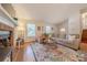 Comfortable living room featuring a brick fireplace, sectional sofa, wood floors, and a large window at 6418 Tivoli Ct, Charlotte, NC 28211