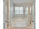 Bathroom showcasing a soaking tub, a separate glass-enclosed shower, and neutral tile at 713 Torrey Pines Ln, Fort Mill, SC 29715