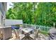 Outdoor patio with stone floor and a metal table with 4 chairs surrounded by a white picket fence and lush trees at 713 Torrey Pines Ln, Fort Mill, SC 29715