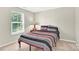 Bedroom filled with natural light features a cozy bed with stylish striped bedding and a bedside table at 7339 Dover Mill Sw Dr, Concord, NC 28025