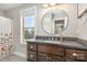 Well-lit bathroom featuring a round mirror, dark countertop, and a window with a view at 7805 Crooked Creek Church Rd, Monroe, NC 28110