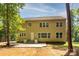 Two-story home featuring a large concrete patio and views of the wooded backyard at 8402 Aspen Ct, Charlotte, NC 28227