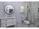 Modern bathroom featuring a sleek vanity, a round mirror, and a glass-enclosed shower at 8402 Aspen Ct, Charlotte, NC 28227