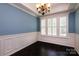 Charming dining room with hardwood floors, wainscoting, and a decorative chandelier at 8402 Aspen Ct, Charlotte, NC 28227