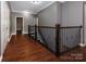 Spacious hallway featuring hardwood floors, iron stair railing, and access to multiple rooms at 8402 Aspen Ct, Charlotte, NC 28227