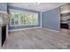 Bright living room with a fireplace, large windows, and light hardwood floors leading to the kitchen at 8402 Aspen Ct, Charlotte, NC 28227