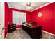 Bright red bedroom featuring dark wood desk, black chair, and modern ceiling fan at 958 Hillard Ln, Lincolnton, NC 28092