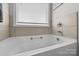 Bright bathroom features a soaking tub with beige tile surround and chrome fixtures at 100 Royal Ave, Albemarle, NC 28001