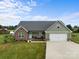 Lovely exterior view of the home featuring a green lawn, brick facade, and attached two car garage at 100 Royal Ave, Albemarle, NC 28001