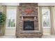 Close-up of a stone fireplace with a hearth and mantel, flanked by windows with plantation shutters at 1116 Arnott Ln, Matthews, NC 28105