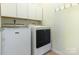 Well-lit laundry room showcasing a white washer and dryer set with white cabinets above at 1116 Arnott Ln, Matthews, NC 28105