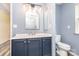 This bathroom features a blue vanity, modern light fixture, and shower with marble-look tile at 12250 Wallace Ridge Dr, Charlotte, NC 28269