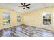 Bright bedroom with three windows, ceiling fan, and wood-look flooring at 12250 Wallace Ridge Dr, Charlotte, NC 28269