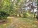 Large, green backyard with mature trees bordering the property and iron fence on the right at 13101 Kensworth Ct, Charlotte, NC 28277