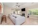 Comfortable living room with a fireplace, large windows, ceiling fan, and a grey sectional sofa at 13510 Brandon Trail Dr, Charlotte, NC 28213