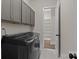 Neutral laundry room features gray cabinets and modern appliances, next to a separate storage closet at 152 Riverstone Dr, Davidson, NC 28036