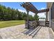 This outdoor kitchen features a stone surround, pergola, stainless steel grill, sink and stone-paved patio at 152 Riverstone Dr, Davidson, NC 28036