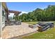 The outdoor living space offers a fire pit, sitting area, outdoor kitchen and stone-paved patio with wooded views at 152 Riverstone Dr, Davidson, NC 28036
