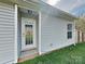 View of the exterior of the home featuring gray siding, a window, a white door and well-maintained lawn at 1703 Southwind Dr, Charlotte, NC 28216
