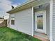 View of the exterior of the home featuring gray siding, a window, a white door and well-maintained lawn at 1703 Southwind Dr, Charlotte, NC 28216