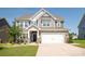 Charming two-story home with a stone facade, a manicured lawn and an attached two-car garage on a sunny day at 17718 Terryglass Ln, Charlotte, NC 28278