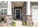 Inviting front porch with stone accents, decorative flowerpots, and a charming welcome mat leading to the front door at 17718 Terryglass Ln, Charlotte, NC 28278